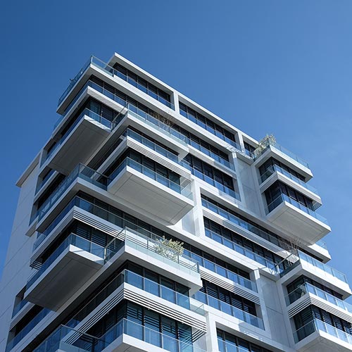 hochhaus-blauer-himmel Ein modernes weißes Hochhaus mit vielen Wohnungen und Balkonen. Der Himmel ist strahlend blau